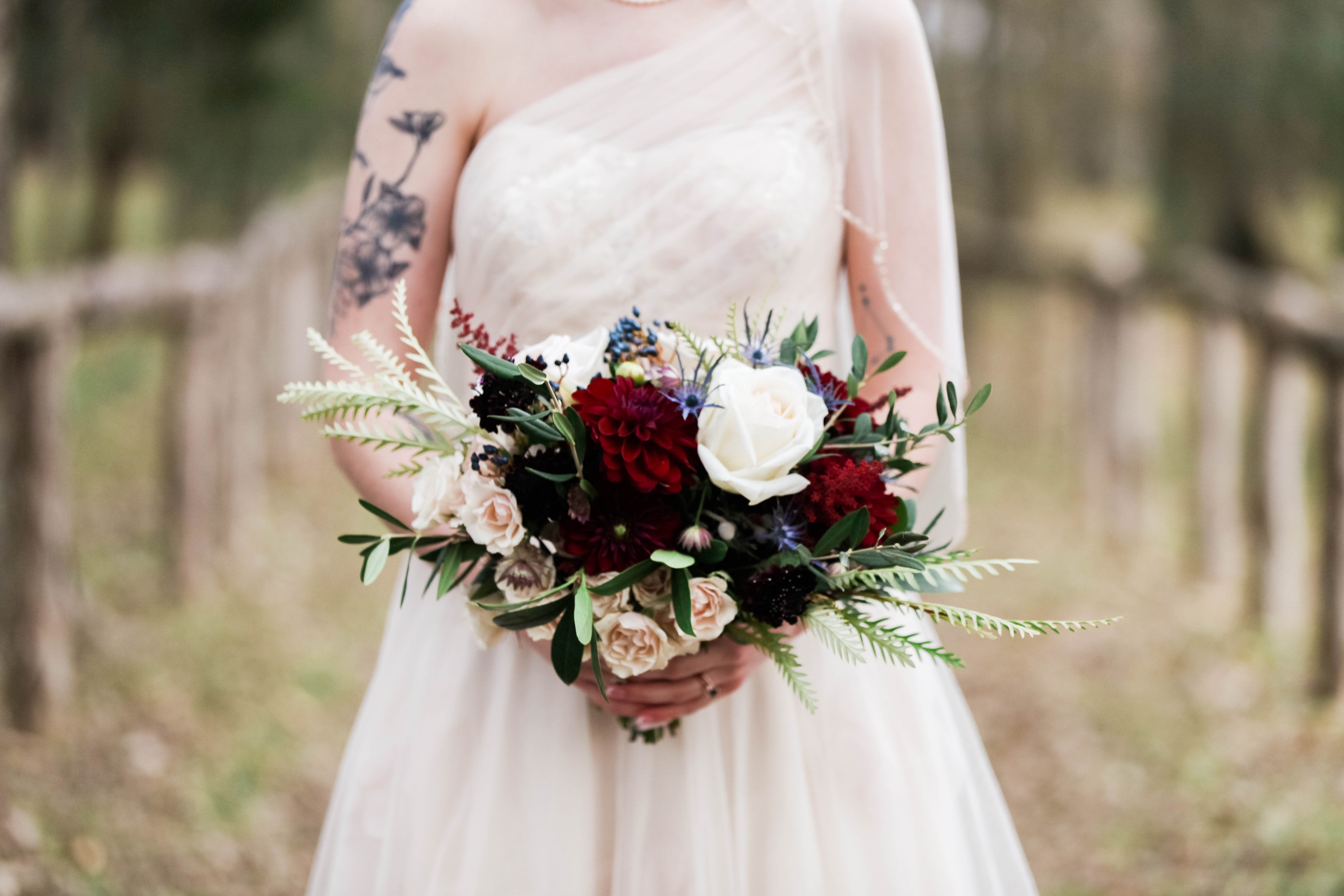 Bride holding a burgundy and cream bouquet with ferns
