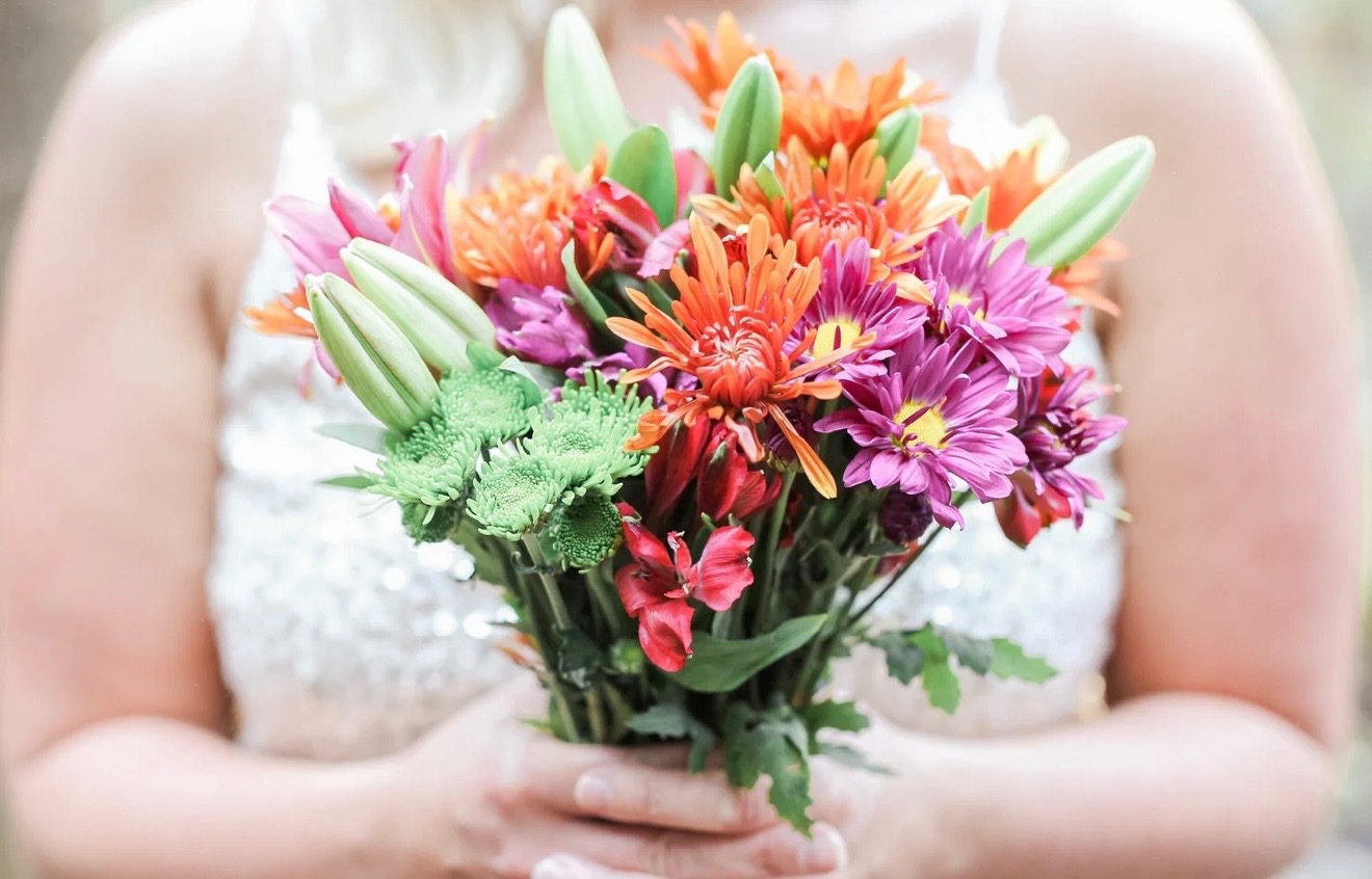 Colorful orange, pink, and green bouquet held by a bride