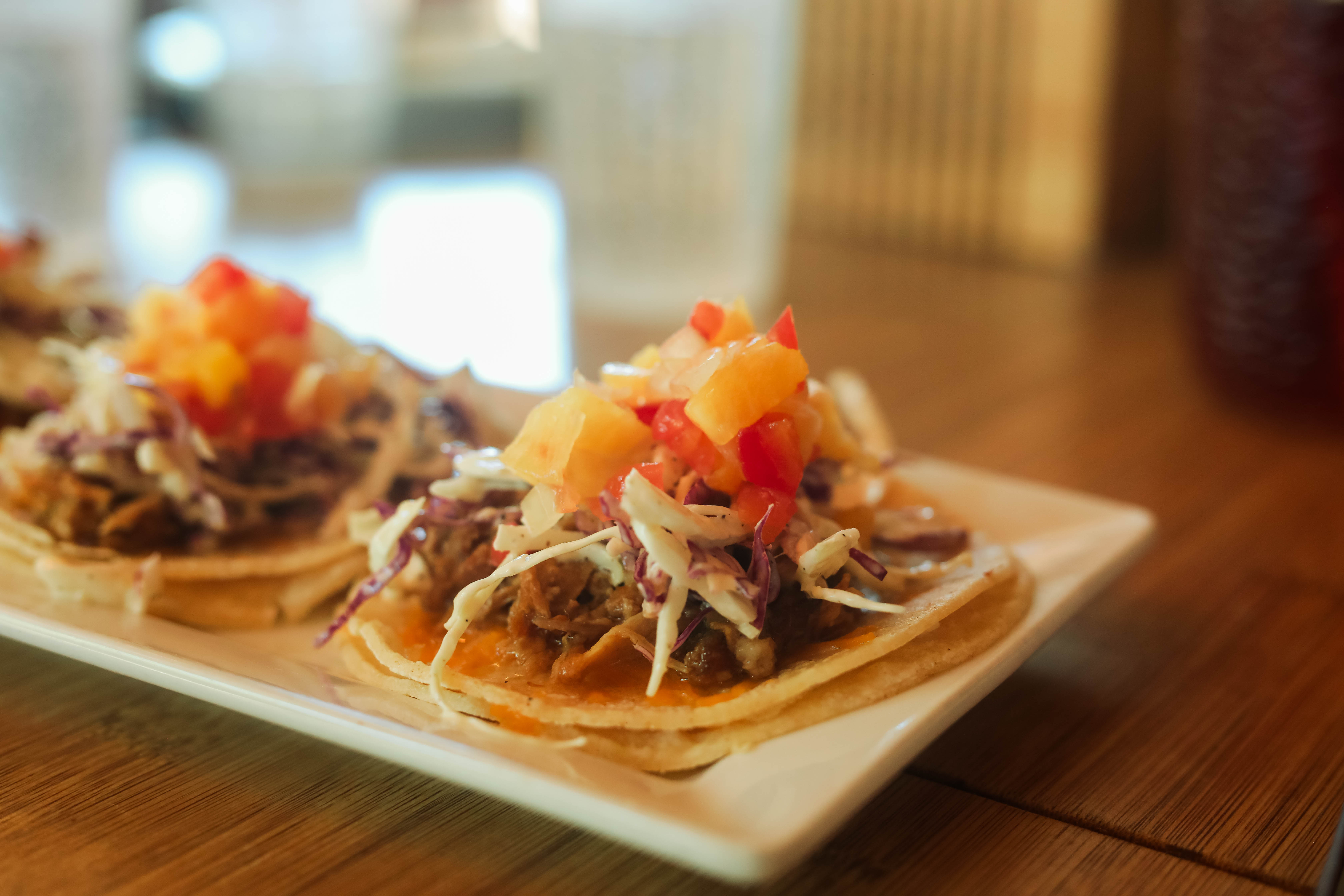 Tacos topped with fresh salsa on a white plate